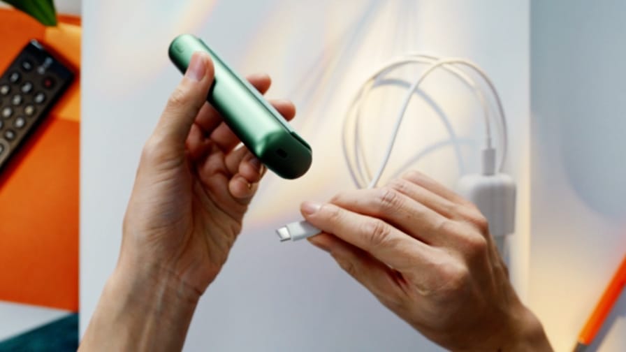 Uzlādes kabelis tiek ievietots IQOS ILUMA PRIME turētājā.