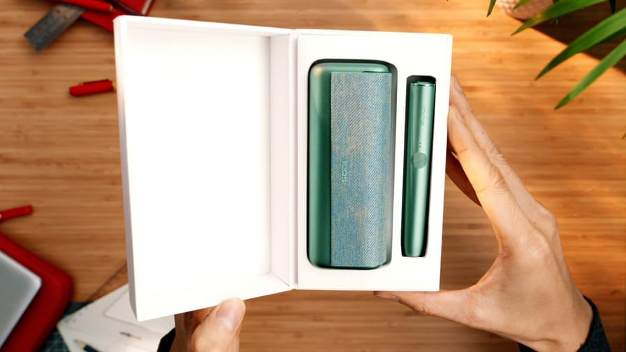 IQOS ILUMA turētājs un portatīvais lādētājs kastē.