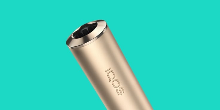 IQOS ILUMA turētājs  Pebble Beige krāsā un uz tirkīza fona
